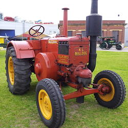 Tractor parked on arena, front left side view.