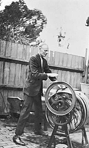 [Tom Cole demonstrating a hand-tumble washing machine, East Brunswick, 1920s.]
