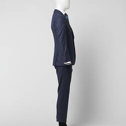 Right profile of blue suit jacket and pants with thin red square check pattern. Branded brown plastic buttons.