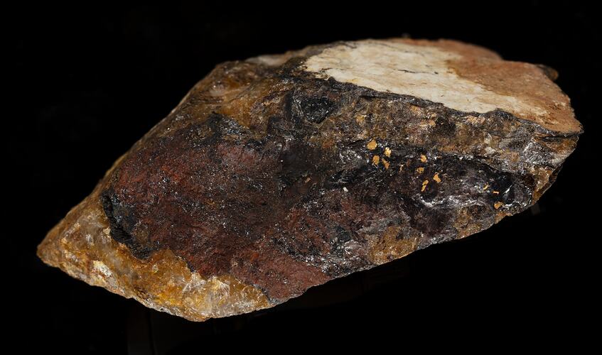 Rock striped with black, brown and red, with gold flecks.