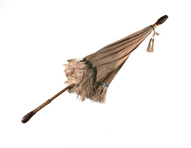 Cream silk parasol with fringed edge and wooden handle, Closed.