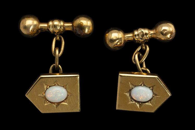 Gold shield shaped cufflinks with central white opals in starcut setting. Chains to barbell togggles.