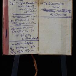 Open book with handwritten text in blue on both pages. Pink cloth tape page marker.