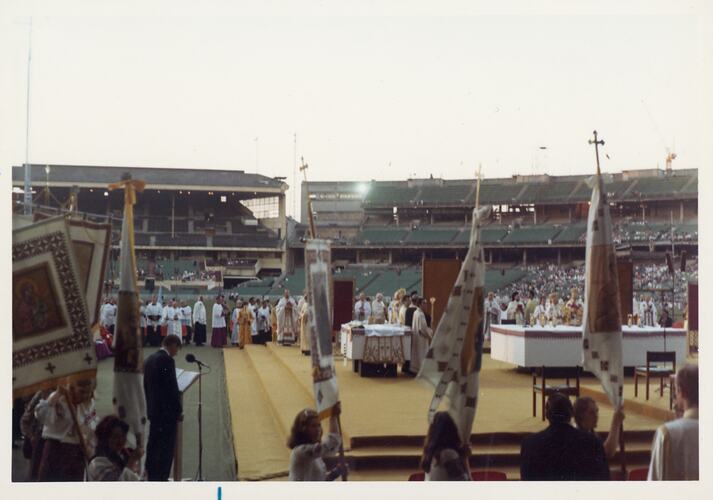 Catholic Mass at the Melbourne Cricket Ground. Religious members stand on stage in centre.