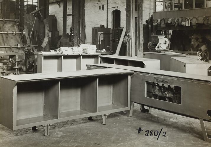 Work and conveyor benches in front of machinery in factory.