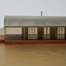 Model of a house with an arched roof, corrugated iron and wide expanses of glass.