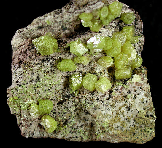 Green crystals on surface of white and black rock.