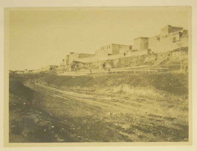 View across empty moat, buildings of Mosul in background.