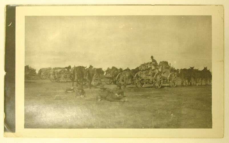 Artillery vehicles, horses and soldiers in a field.