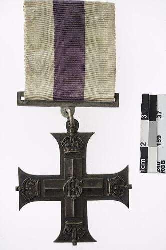 Metal cross with white and purple ribbon.