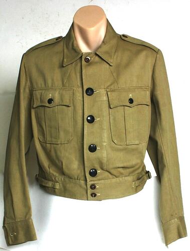 Khaki jacket, cropped, with two breast pockets. Dark brown bakelite buttons.
