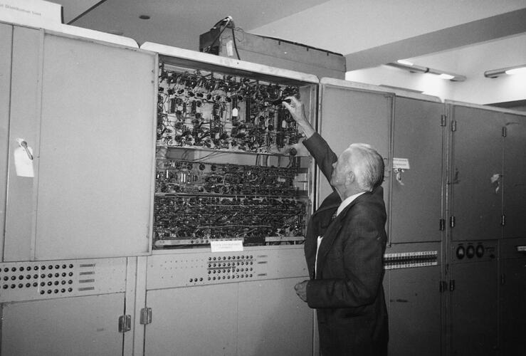 Older man demonstrating or adjusting computer circuitry.