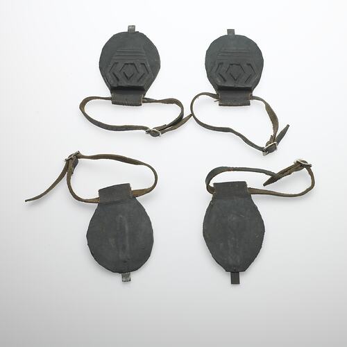 Four black horse shoe soles with straps.