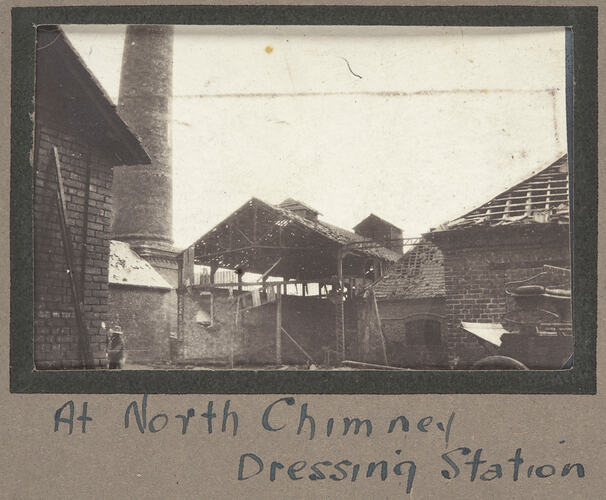 Damaged buildings with large chimney in the background.