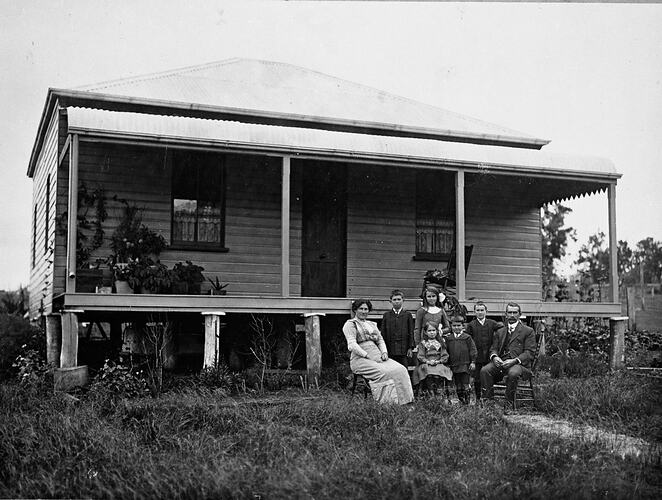 Family out the front of a weatherboard house in rural setting.