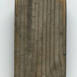 Back of worn, wooden paddle-shaped bat.