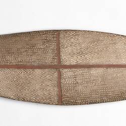 Wooden shield with incised decorations and pointed ends.