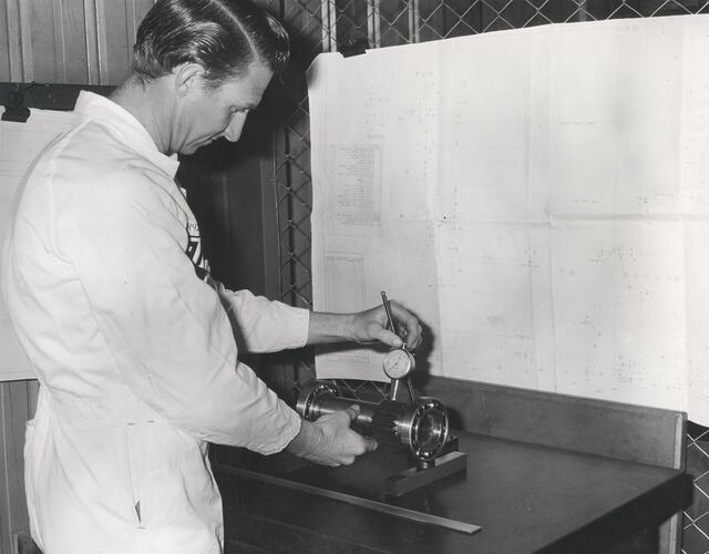 A man using a micrometer measuring a gear.