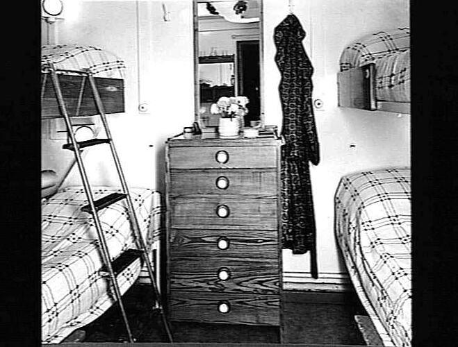 Ship interior. Bunk beds on left and right. Chest of drawers in centre.