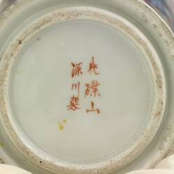 White base of vase with six red painted Chinese characters.