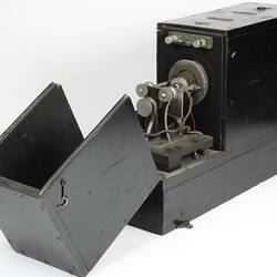 Grey box, open to show metal machine parts inside.
