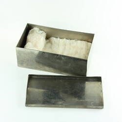 Metal rectangular box, lid off. Contains cotton gauze.