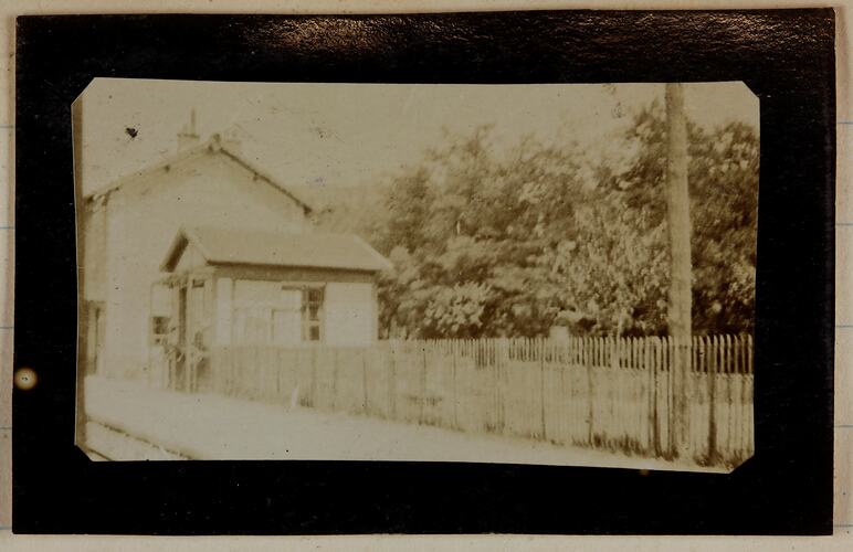 View of a house and picket fence near a railway.