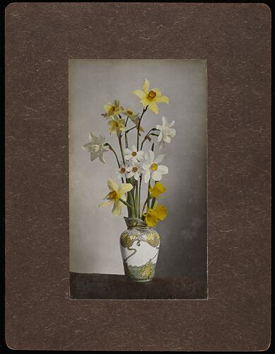 Still life of yellow and white flowers in a white vase.