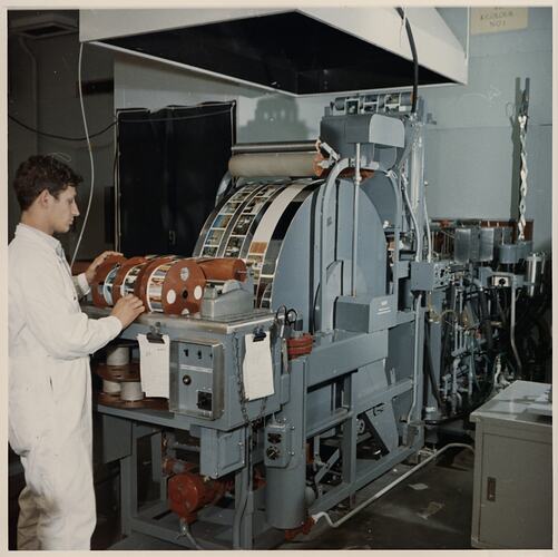 Worker adjusting machine rolled with colour photographs.