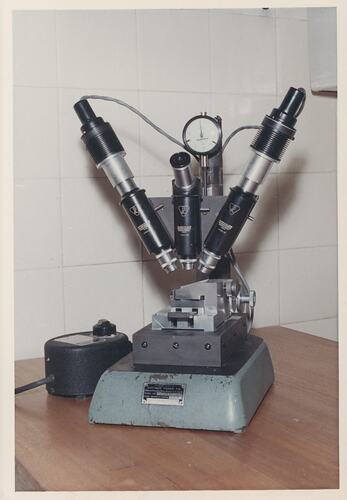 Three lensed microscope on bench.