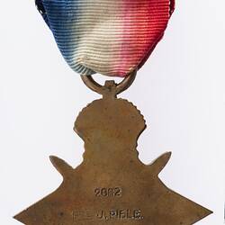 Back of star-shaped medal with red white and blue striped ribbon.