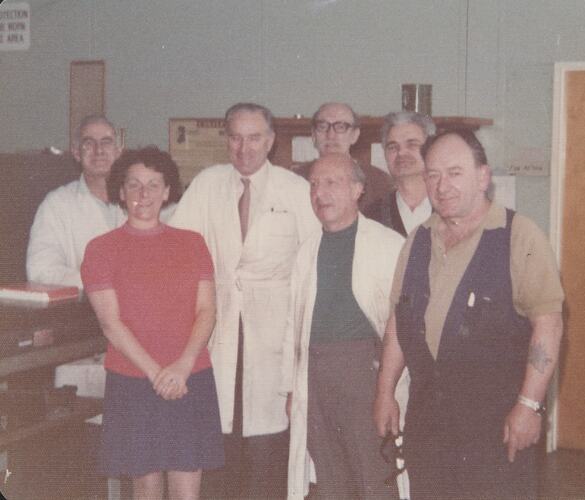Group of men and one woman in workshop.