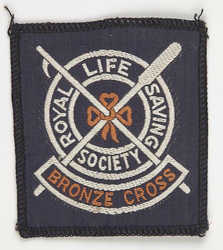 Blue square cloth badge with white and orange logo of a life buoy (ring) and crossed boat hook and oar.