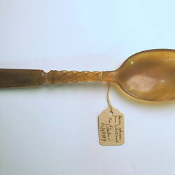 Horn spoon with paper label viewed from above.