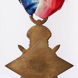Back of bronze four point star medal 'ensigned' by a crown. Red, white and blue ribbon.