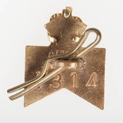 Reverse of metal badge, ribbon shape, crown atop. Button hole pin.