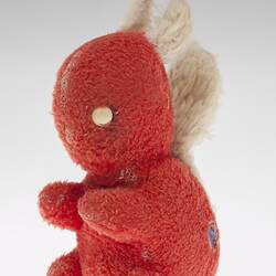 Left view of red plush toy squirrel with two white button eyes, white ears and tail.