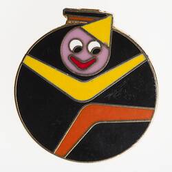 Round black enamelled badge depicting the yellow and red boomerang clown logo of the Melbourne Moomba festival