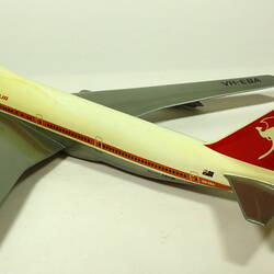 White model plane with red trim and tail. Grey wings. Left rear three quarter view.