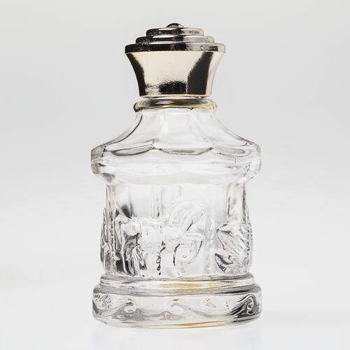 Glass carousel shaped perfume bottle, gold plastic lid. Carousel has horses, swans.