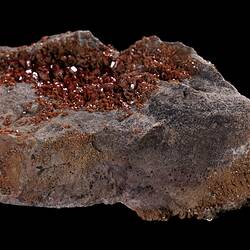 Red-orange crystals on grey rock.