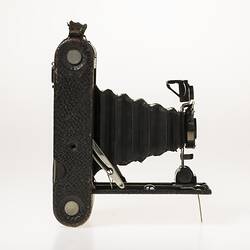 Black camera with leather covering. Folds out with bellows, metal brackets. Right profile.