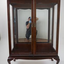 Wooden framed crystal cabinet. Glass doors and sides mirror at back. Front view, doors closed.