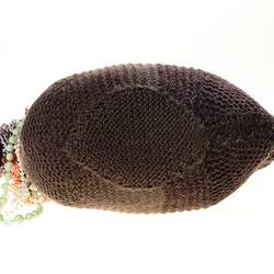 Hand-knitted brown chicken with pink rosettes and necklaces around its neck. Top view.