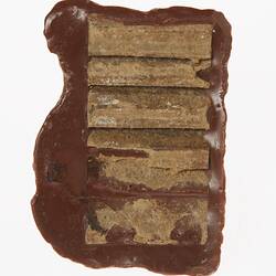 Back of brown painted plaster model of chocolate koala. Has remnants of adhesive horizontal strips.