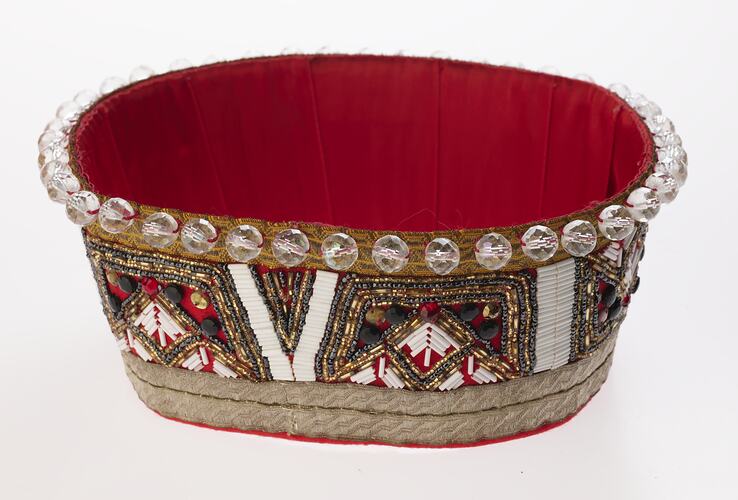 Red fabric crown decorated with clear beads and trimming.