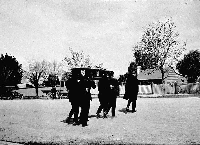 [Pallbearers carrying a coffin, about 1927.]