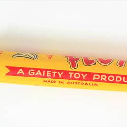 Yellow plastic toy flute with red lettering.