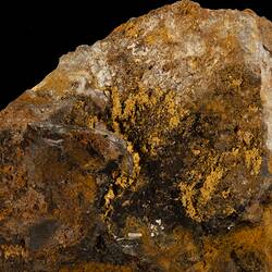 Irregular orange and brown rock with gold streaks.