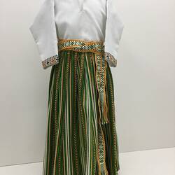 Child's national costume. Cream long-sleeved shirt, green/brown long pleated skirt, woven belt.